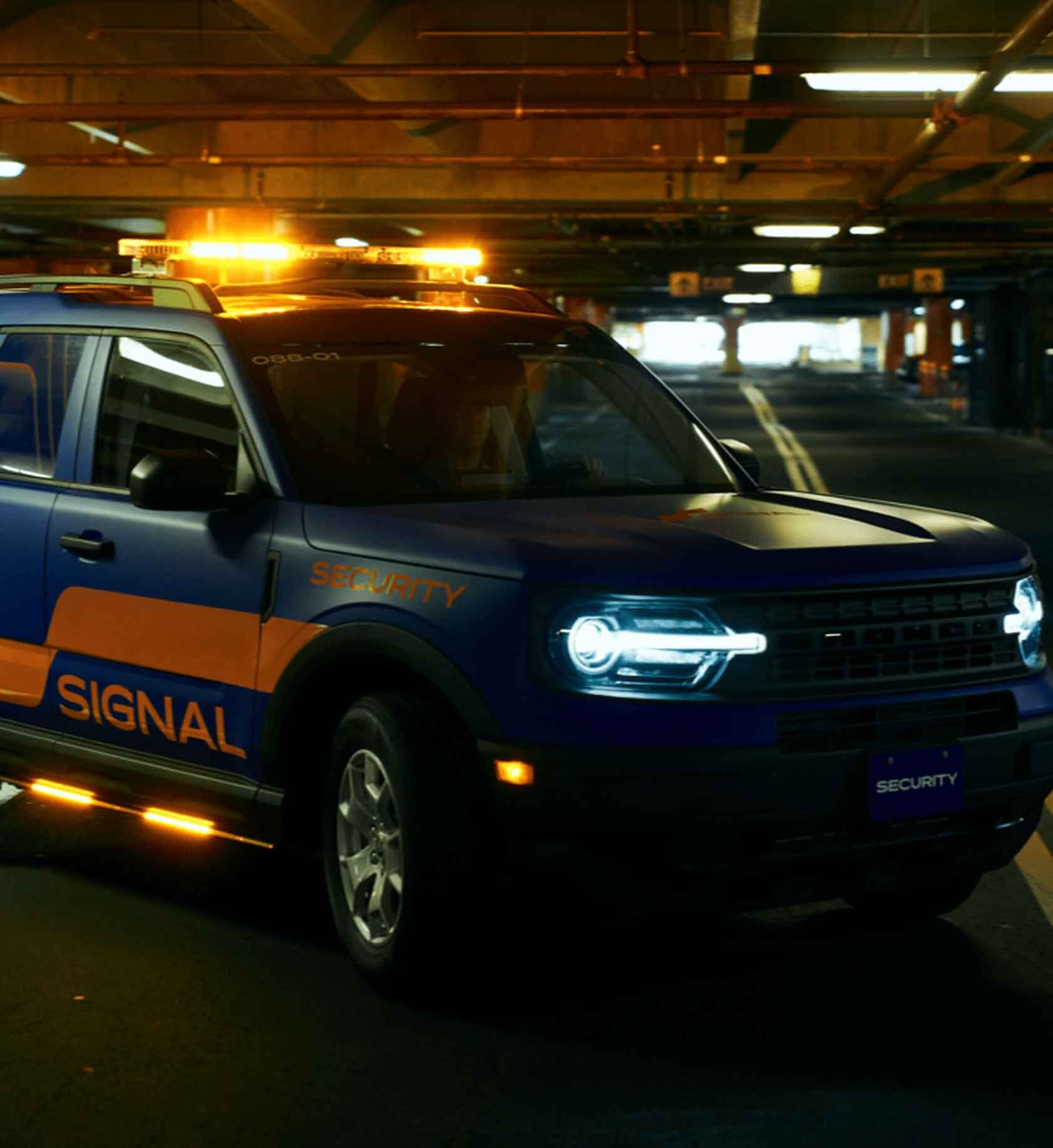 Signal security services company vehicle with its lights on in a dark parking garage