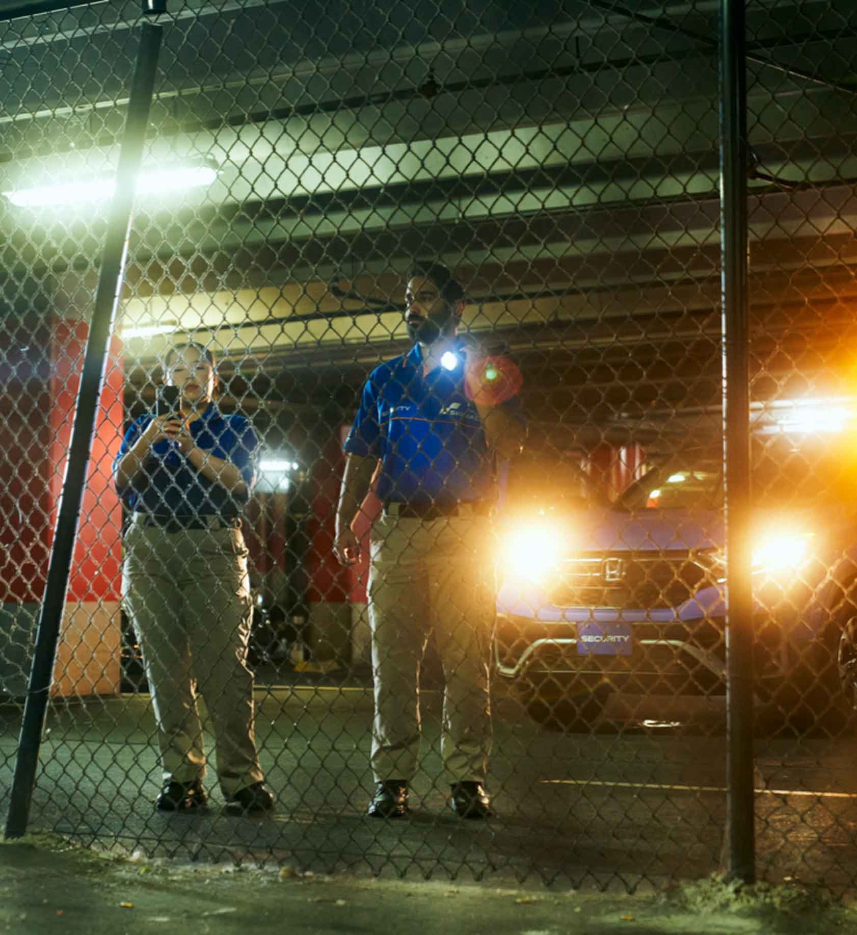 Signal employees shining flashlights through a chainlink fence