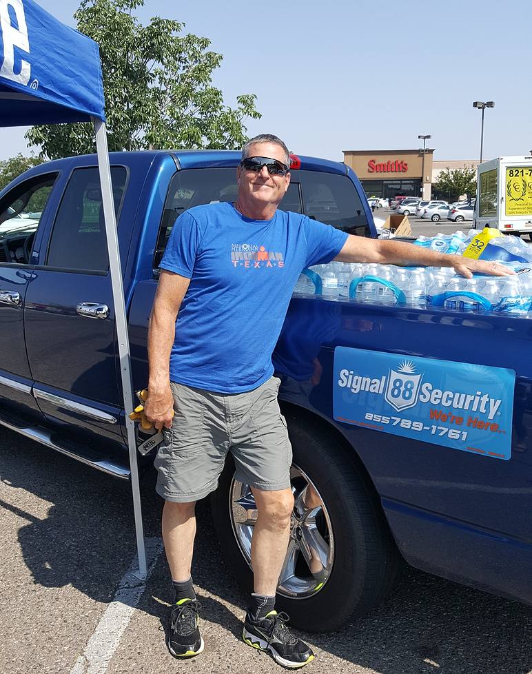 Signal volunteer leans on truck full of water bottles