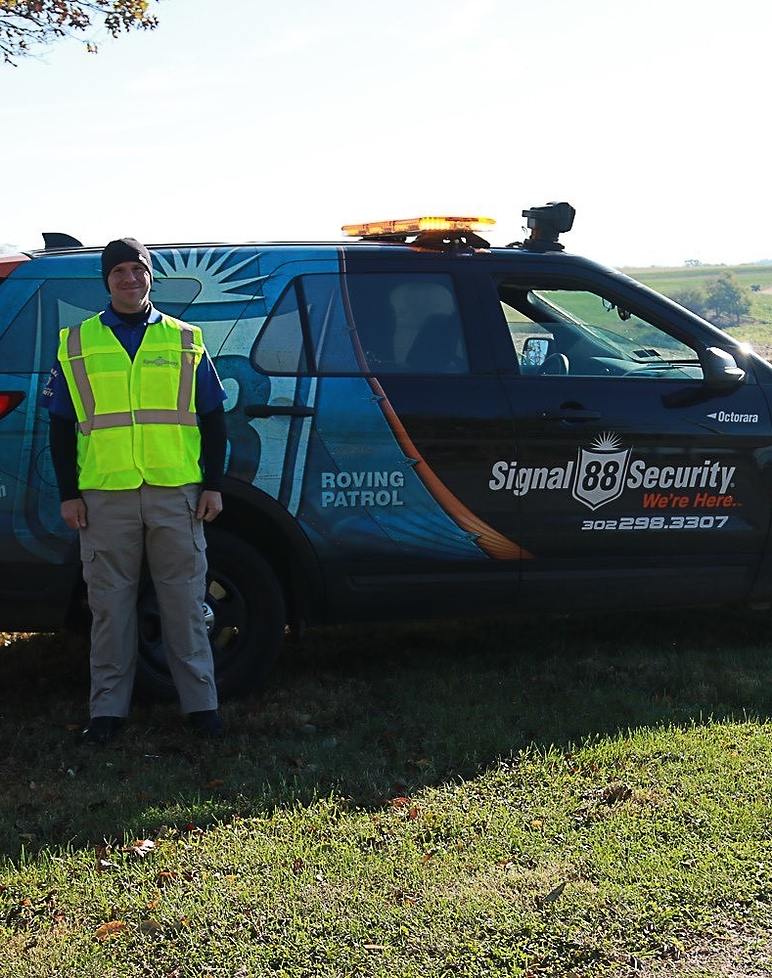 person wearing safety vest standing in front of a Signal company vehicle