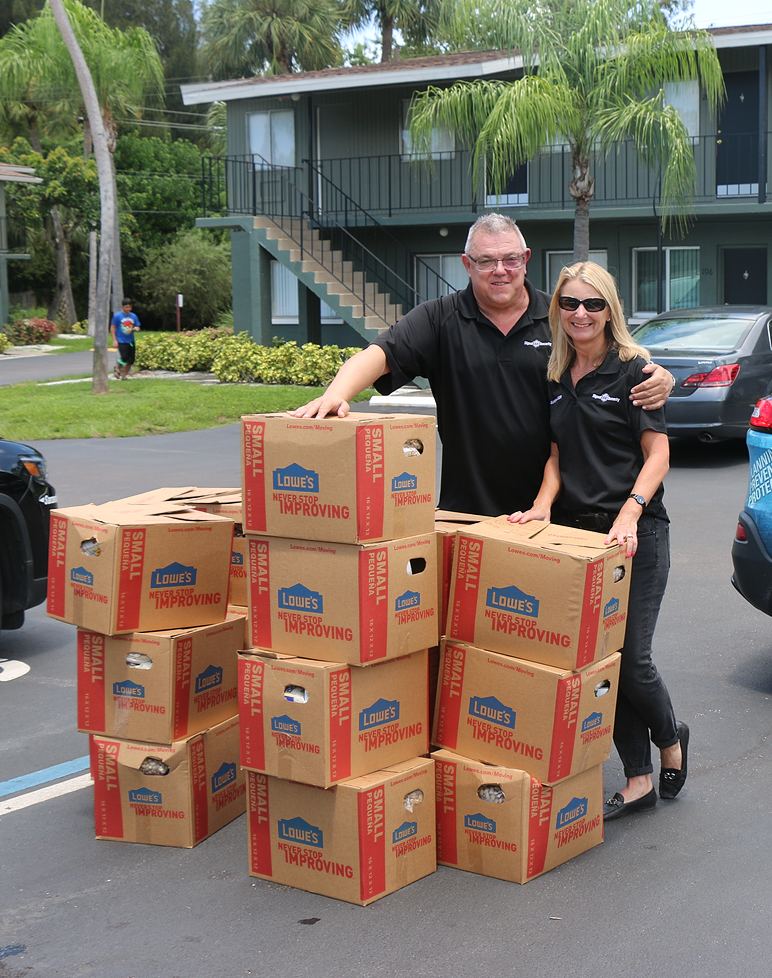 two people wearing volunteer shirts standing with several food boxes